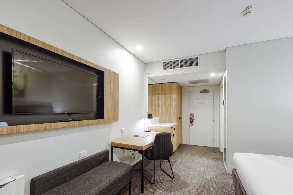 Een moderne hotelkamer met een flatscreen televisie, een bureau met stoel, een sofa en een bed.