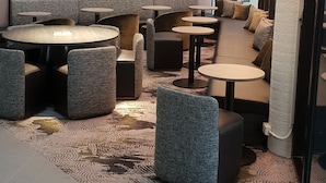 A modern lounge area with a stone wall, cushioned seating, and round tables.