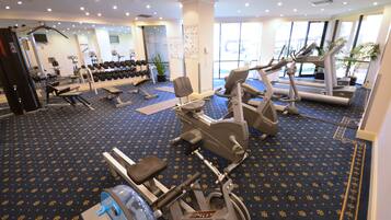 Una palestra con macchinari cardio, panche per pesi e manubri.