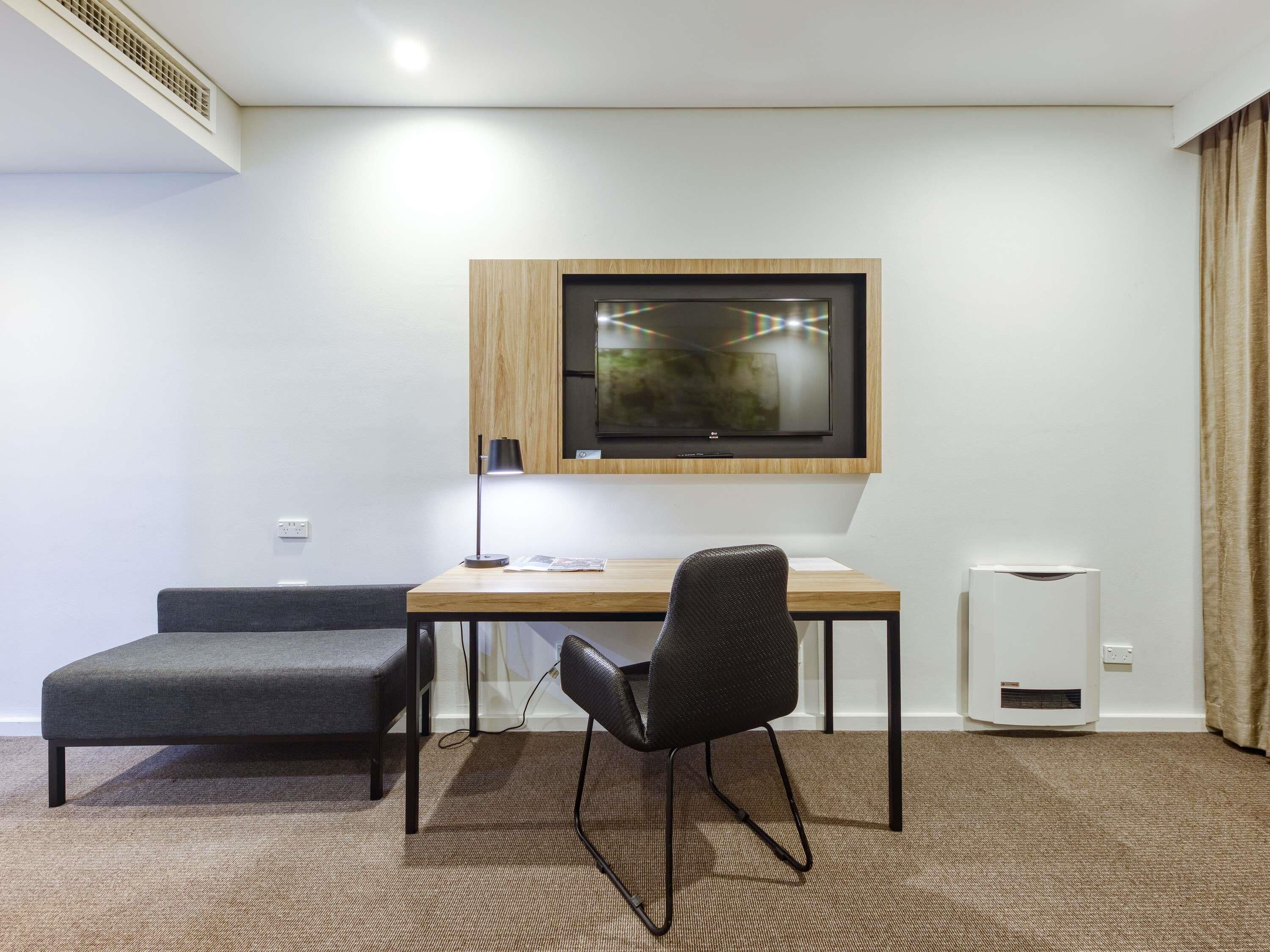 Una habitación moderna con escritorio, silla y televisor montado en la pared.