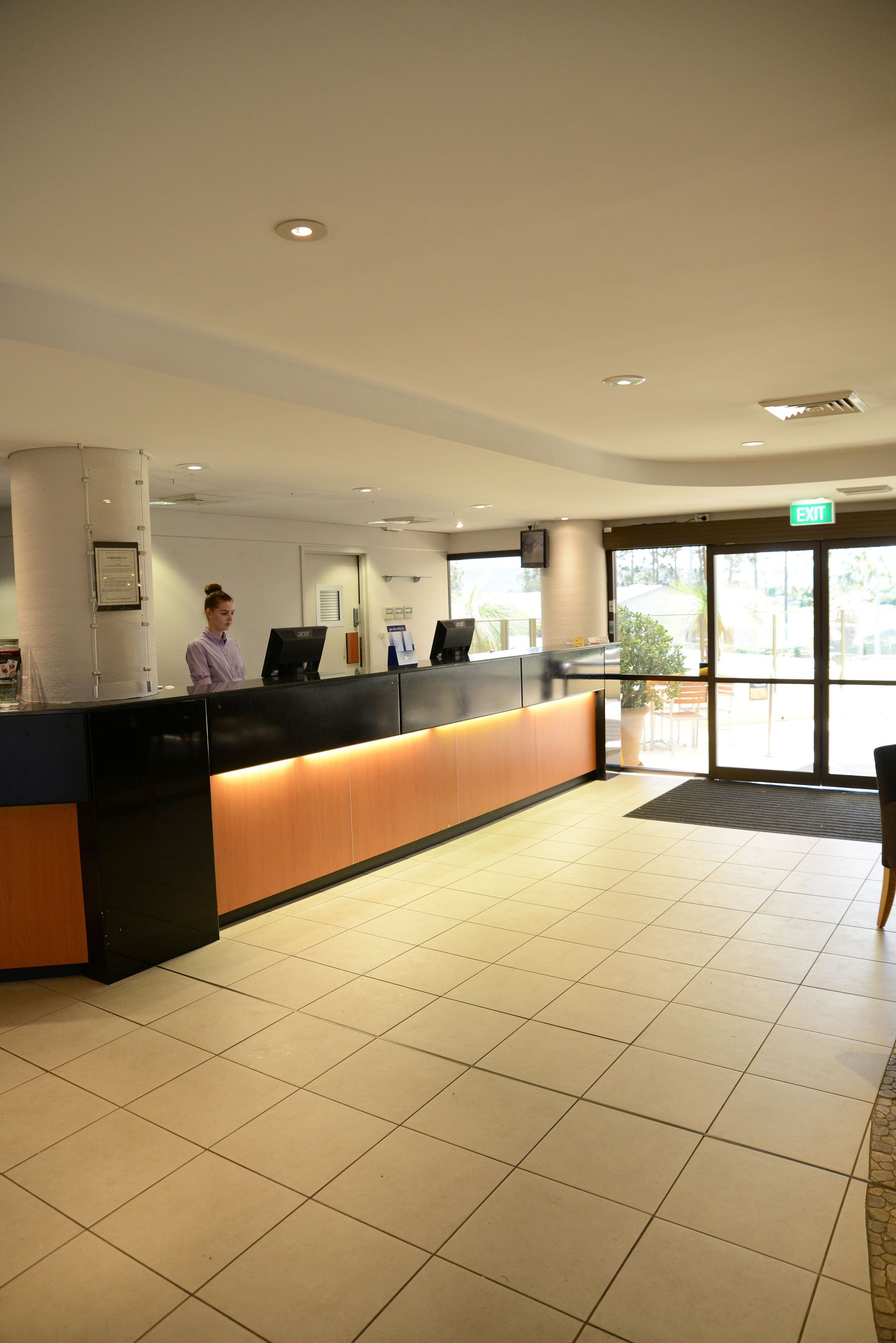 A reception area with a counter, a receptionist, a computer, and a door leading outside.
