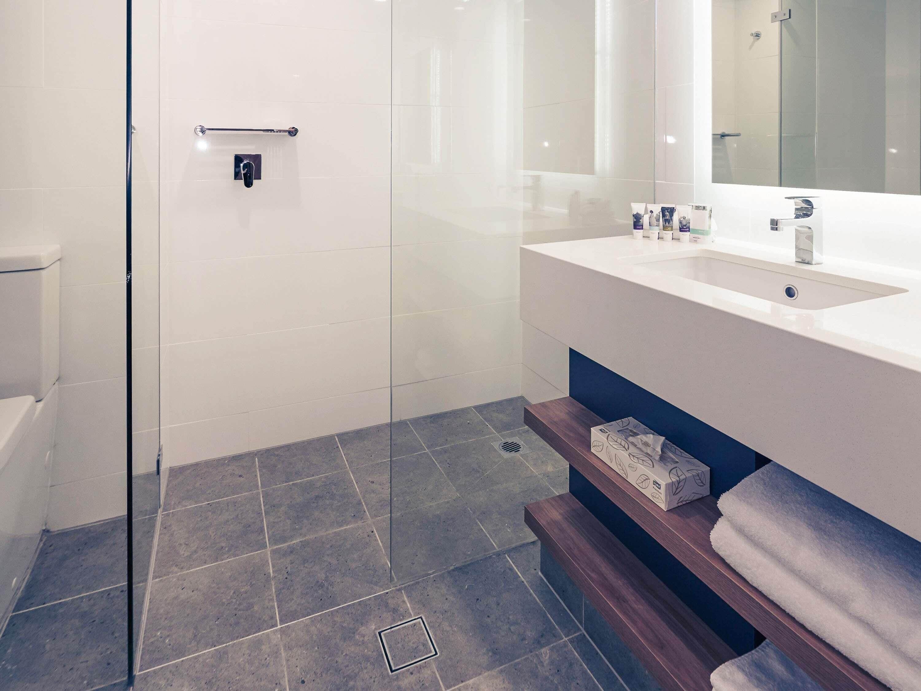 Un baño moderno con cabina de ducha de vidrio, un lavabo blanco y un espejo sobre él.