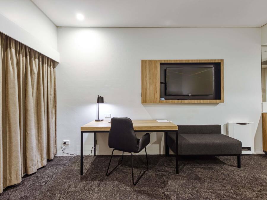 Una habitación pequeña y moderna con un escritorio, una silla y un televisor montado en la pared.