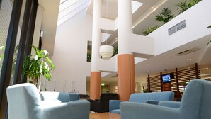 A modern lobby with seating, a reception desk, and a TV screen.