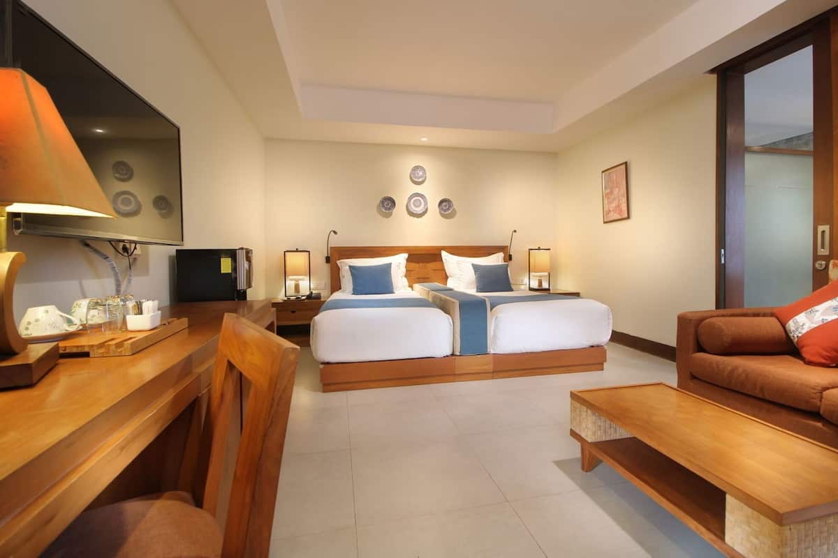 A hotel room with a bed, a desk, a chair, a sofa, and a TV.