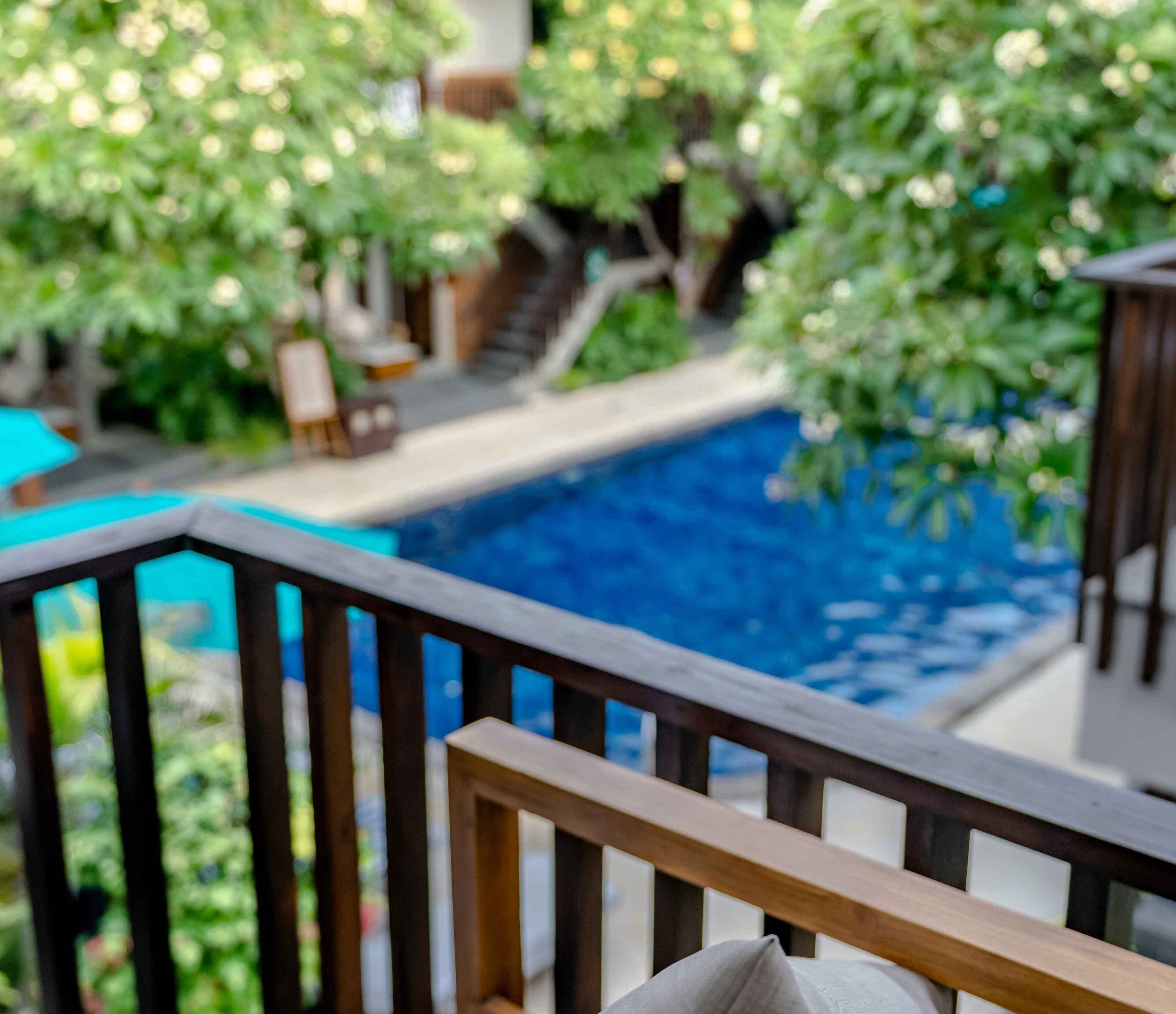 Area piscina con terrazza in legno e vista su un giardino rigoglioso.