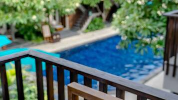 Área de piscina com deck de madeira e vista para um jardim exuberante.