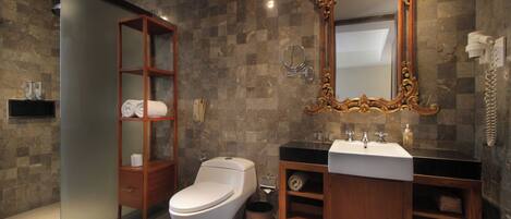 A modern bathroom with a toilet, vanity, and a large ornate mirror.