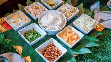 Une table sur laquelle sont disposés divers aliments, présentés sur des feuilles de bananier.