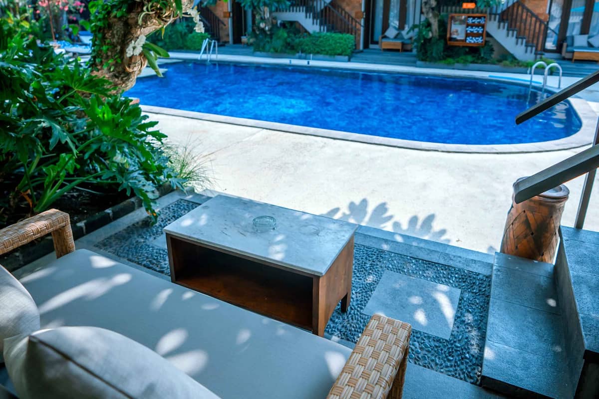 A poolside area with a seating arrangement, a pool, and a staircase leading to a building.
