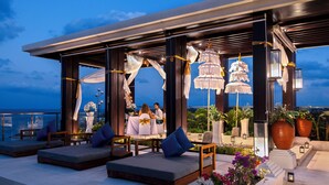 An outdoor seating area with cushioned benches and tables, a decorative archway, and potted plants. - Bali Tropic Resort & Spa (Nusa Dua)