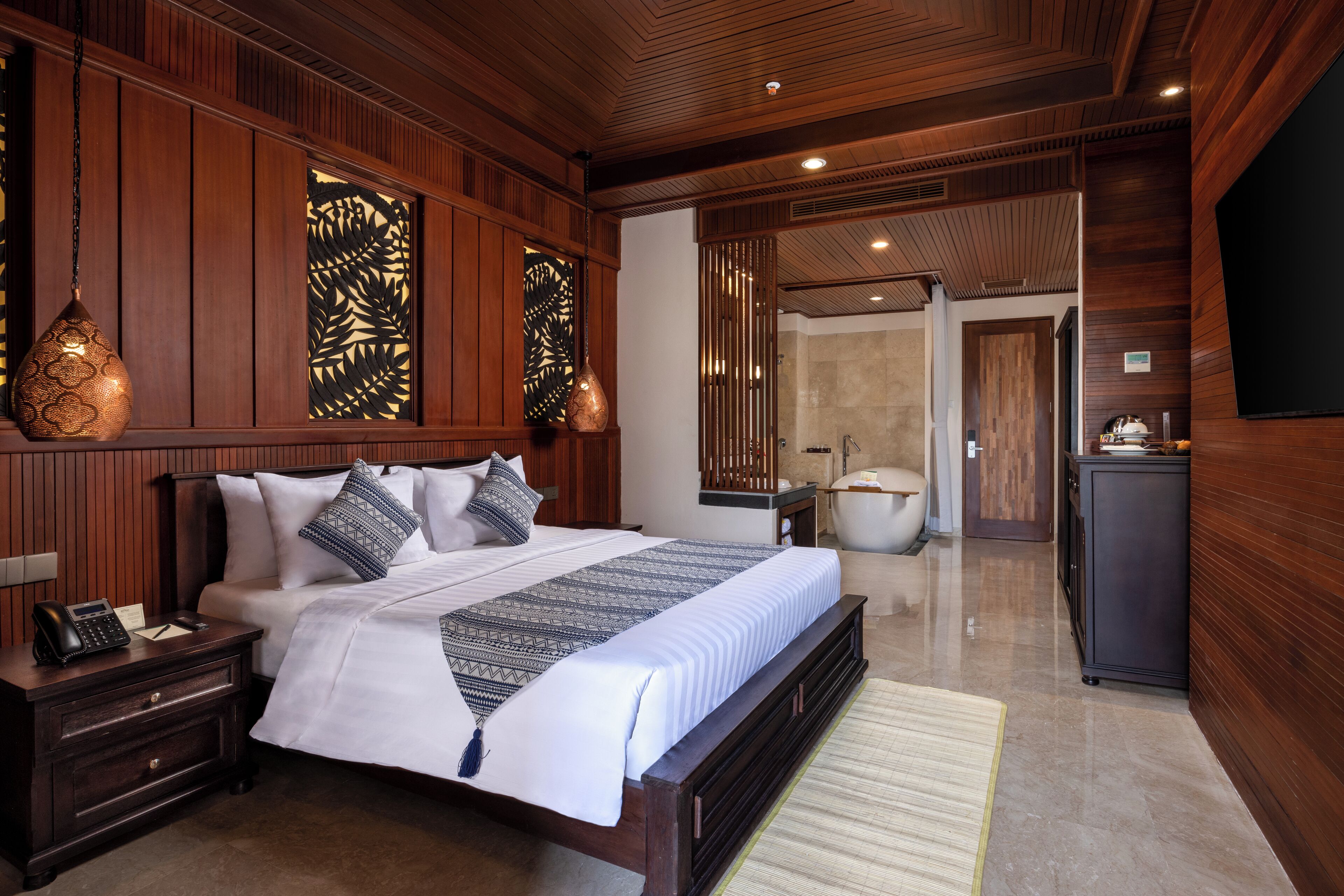 Un dormitorio espacioso con una cama grande, paneles de madera, una tocador con espejo y una bañera en el baño contiguo.