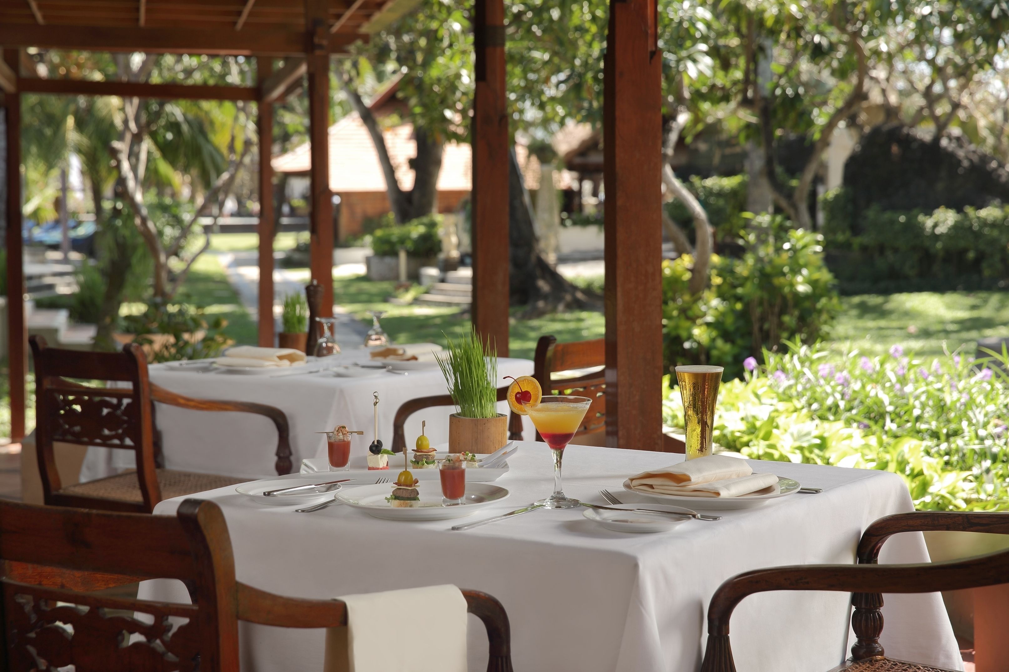 Un restaurant doté d’une terrasse, de tables recouvertes de nappes blanches et proposant un choix varié de plats et de boissons.