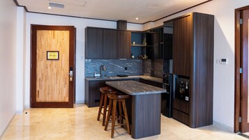 A modern kitchen with dark wood cabinets, a marble backsplash, and a built-in island with stools.