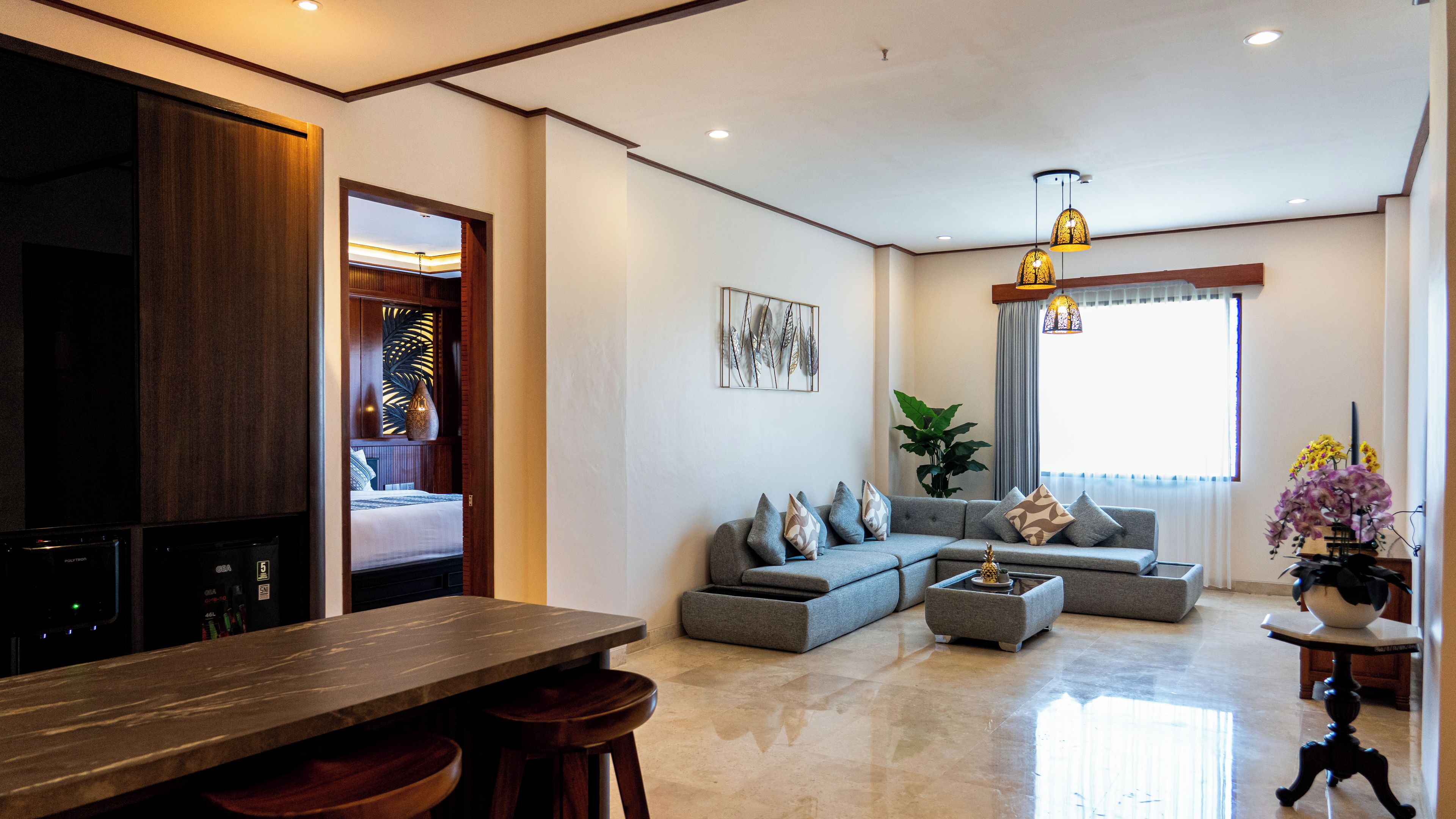 A modern living room with a sofa, coffee table, and a dining area with a wooden table and bar stools.