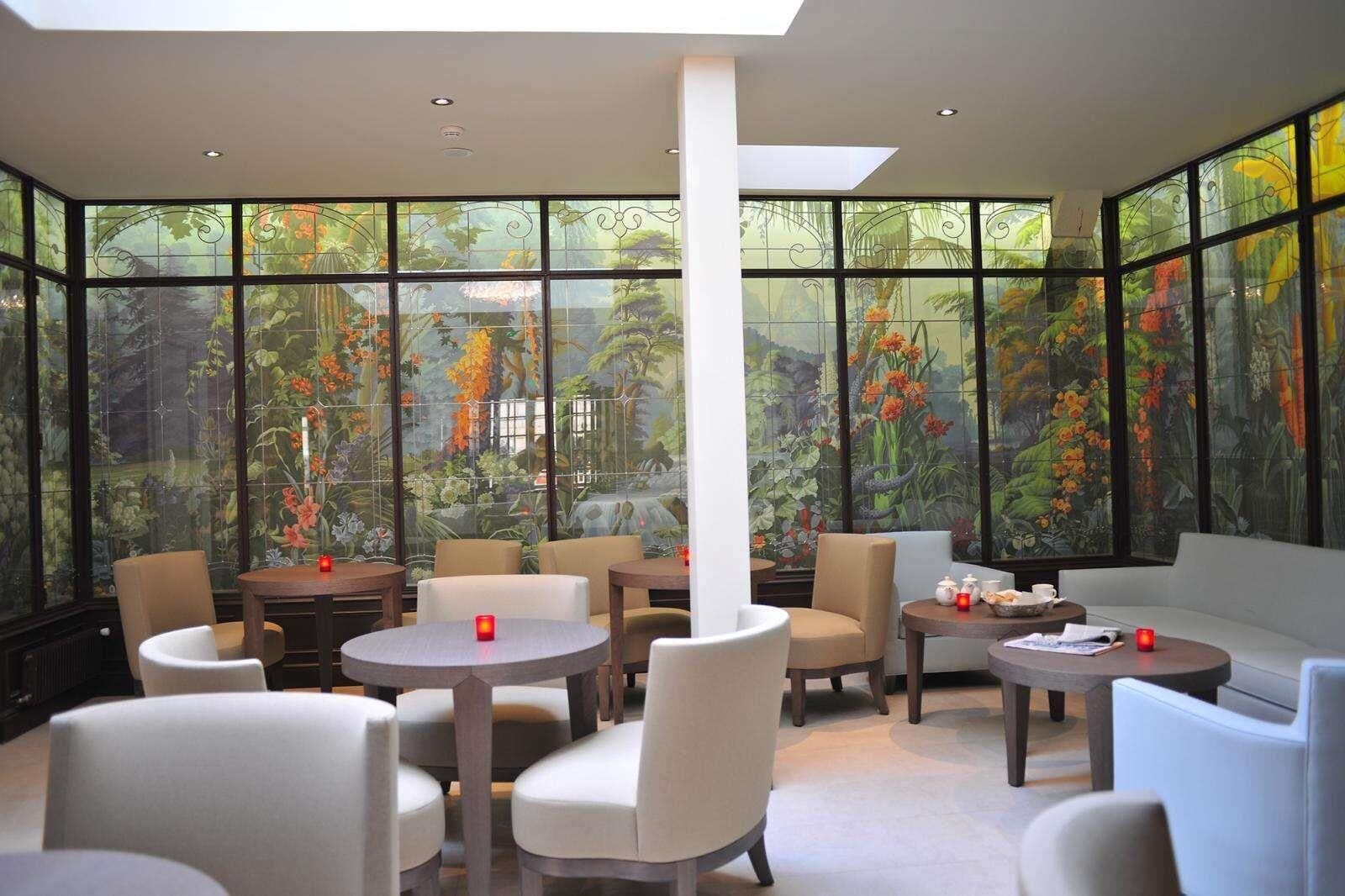 A modern interior with large windows, round tables, and comfortable seating.