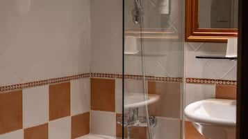 A bathroom with a glass-enclosed shower, a white bathtub, and a sink with a mirror above it.