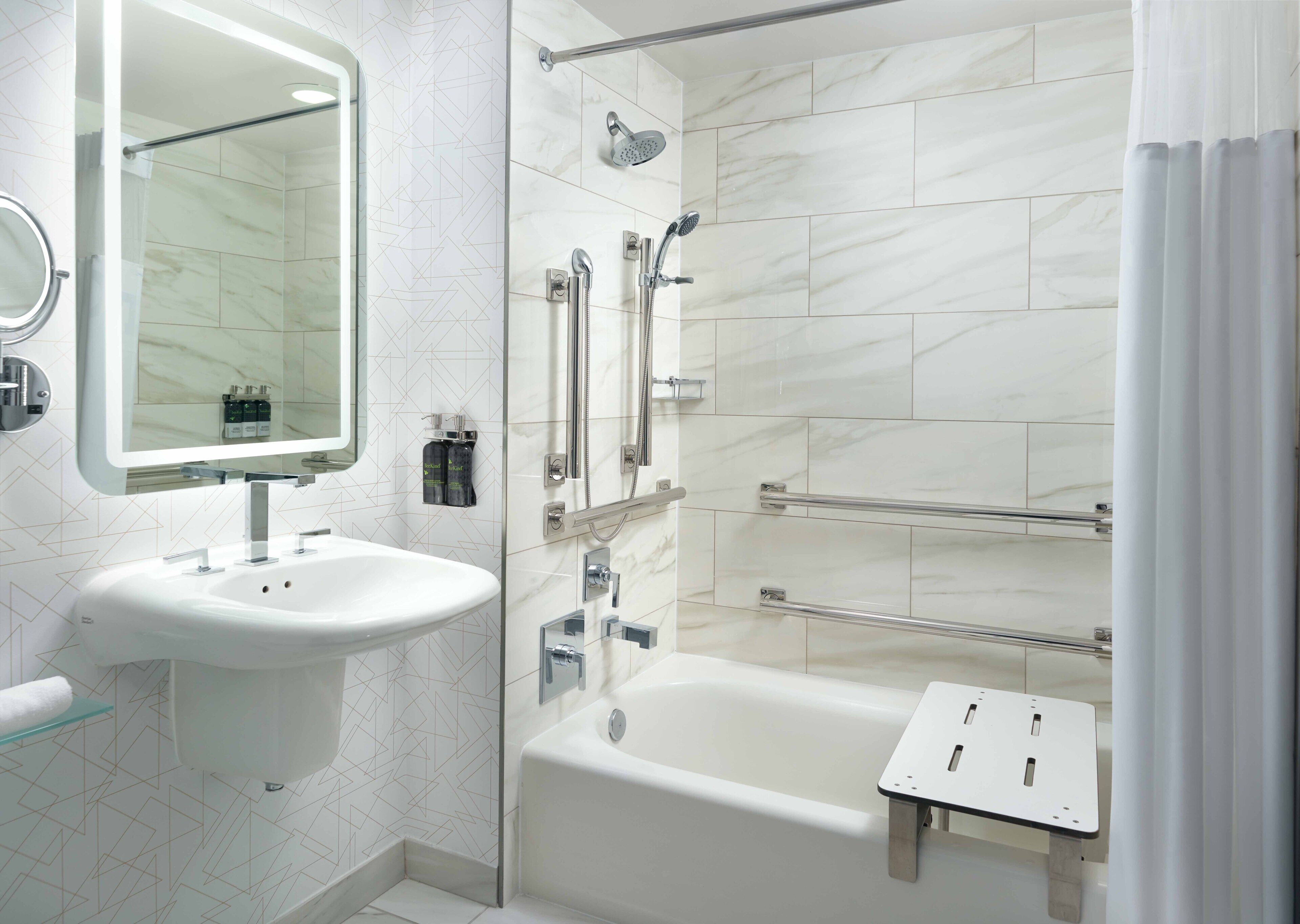 A modern bathroom with a white sink, mirror, and shower.