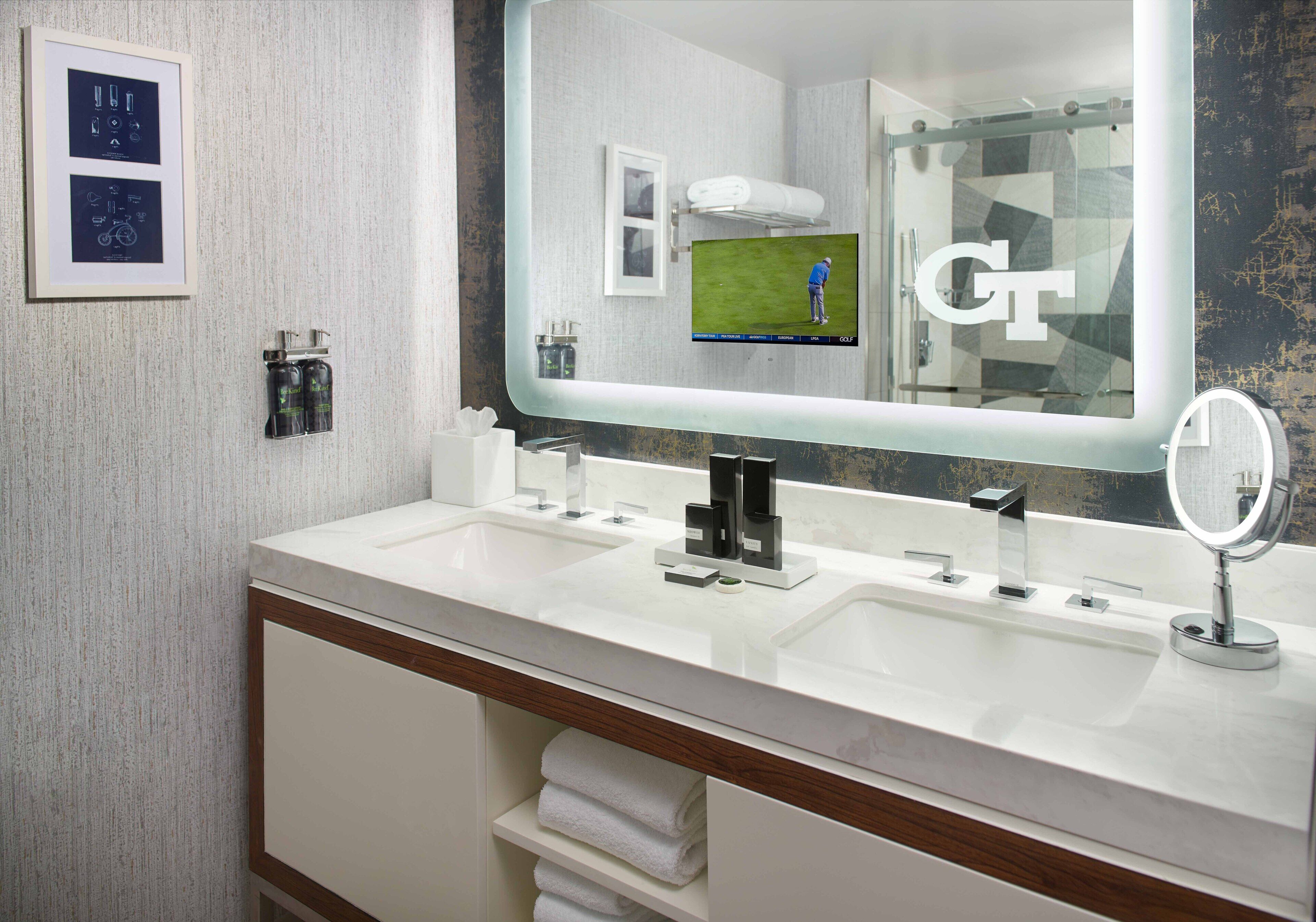 Un baño moderno con dos lavamanos, un espejo grande y un perchero para toallas.