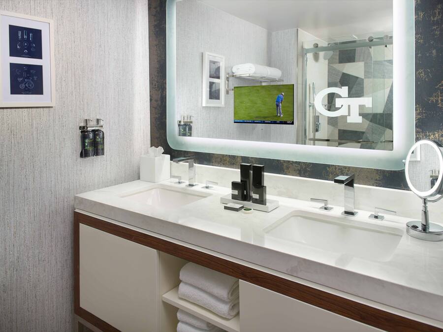 Un baño moderno con dos lavamanos, un espejo grande y un perchero para toallas.