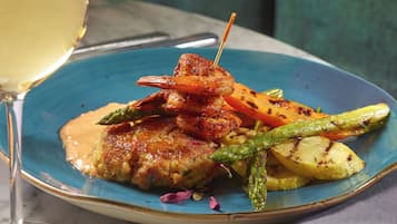 A plate of food with grilled vegetables and a piece of meat, accompanied by a glass of white wine.
