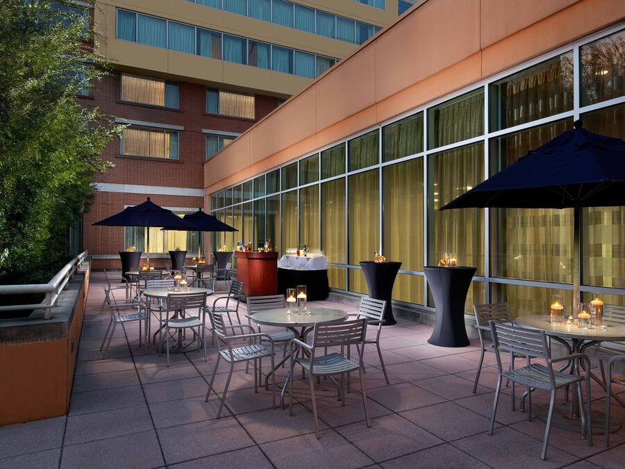 An outdoor patio with tables and chairs, large umbrellas, and candles.