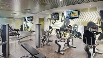 A modern gym with various exercise equipment, including dumbbells, benches, and cardio machines.