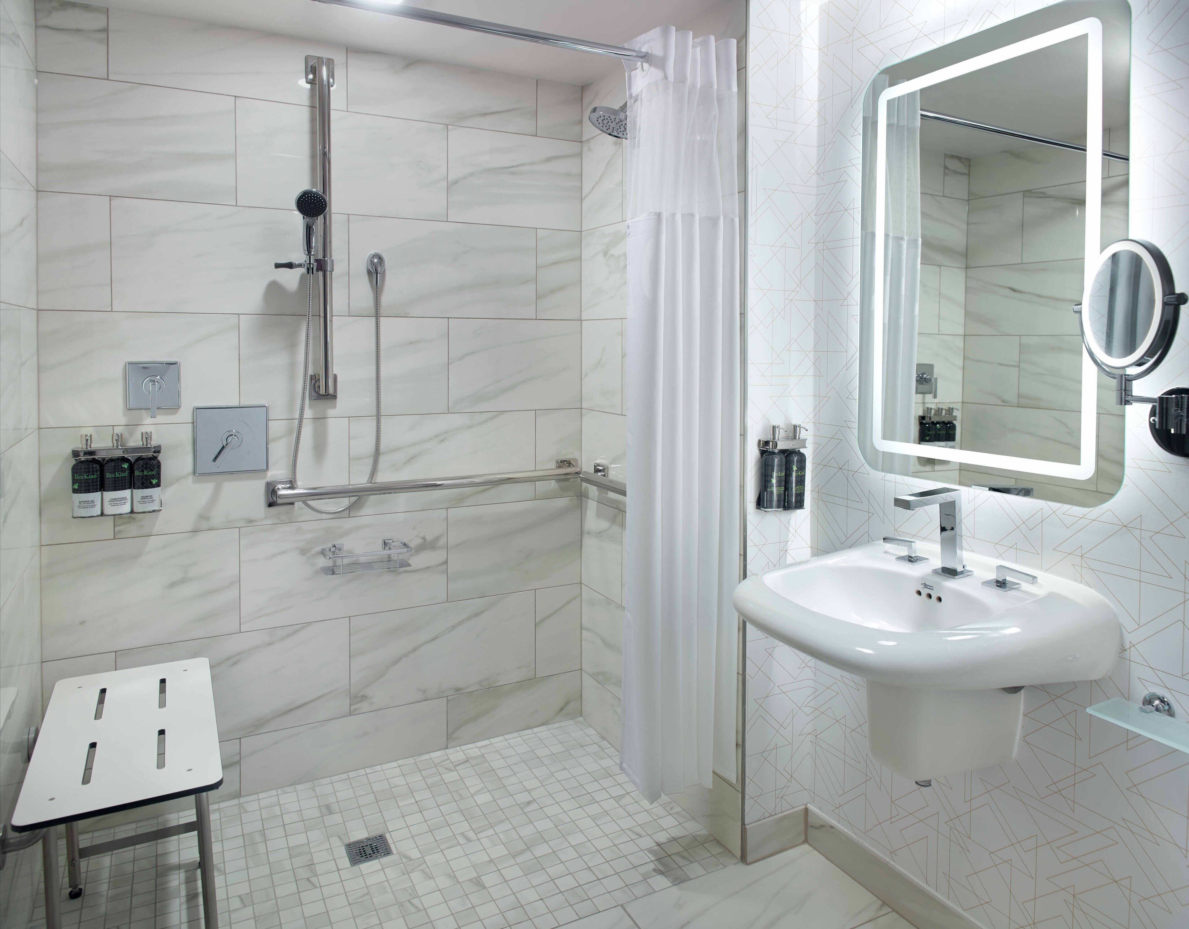 A modern bathroom with a shower, a sink, a mirror, and a toilet.