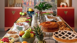 A buffet table with various food items, a decorative wall with a mural, and a red cabinet. - Hotel Milani (Rome)
