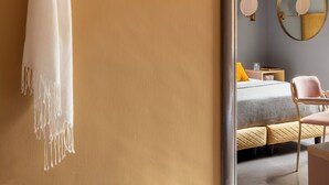 A room with a bed, a chair, a suitcase, a mirror, and a towel hanging on a wall. - Hotel Milani (Rome)