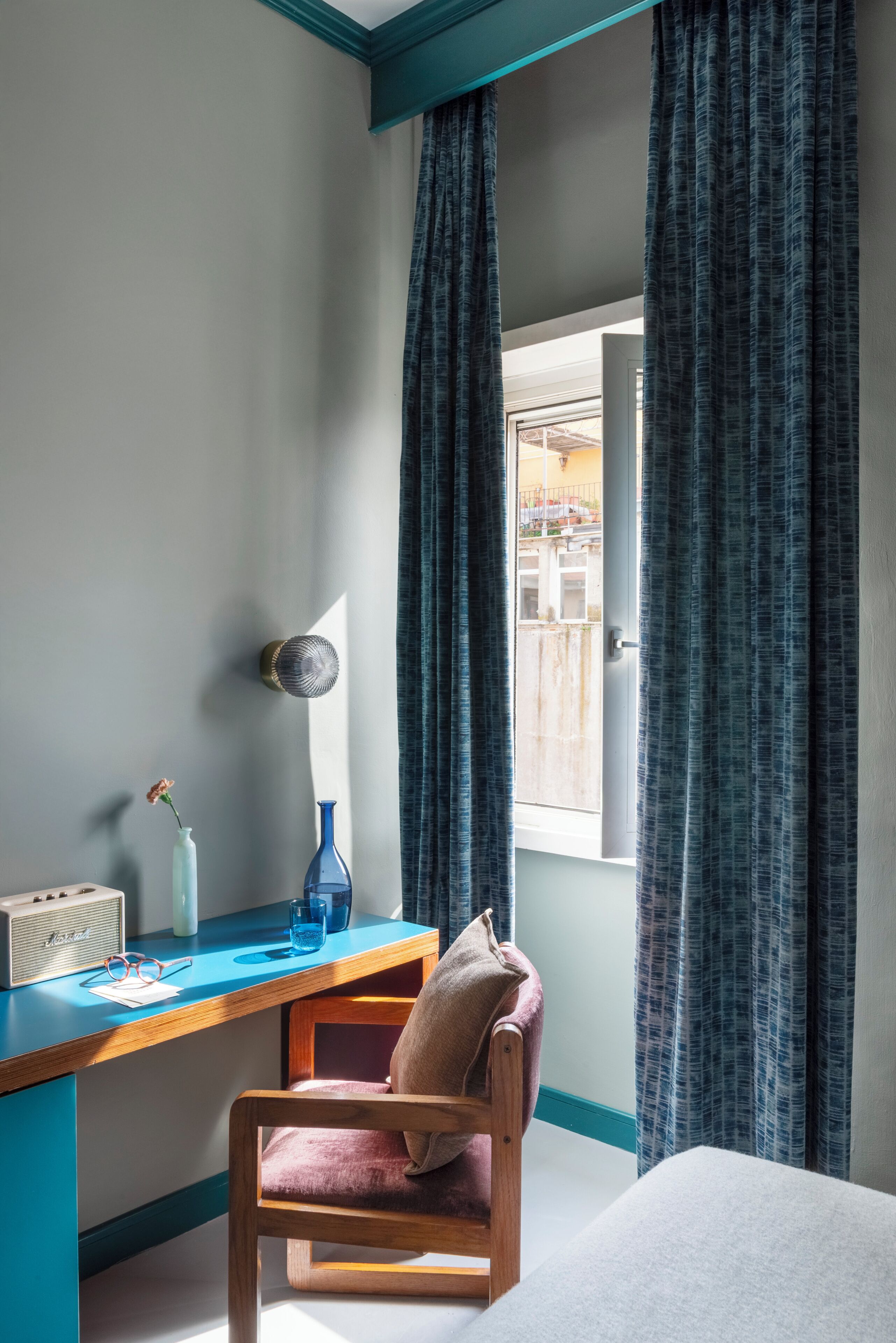 A room with a desk, chair, and a window with curtains.