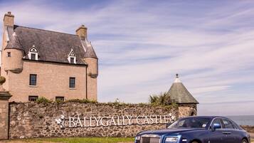 A large stone building with a sign reading "BALLYGALLY CASTLE".