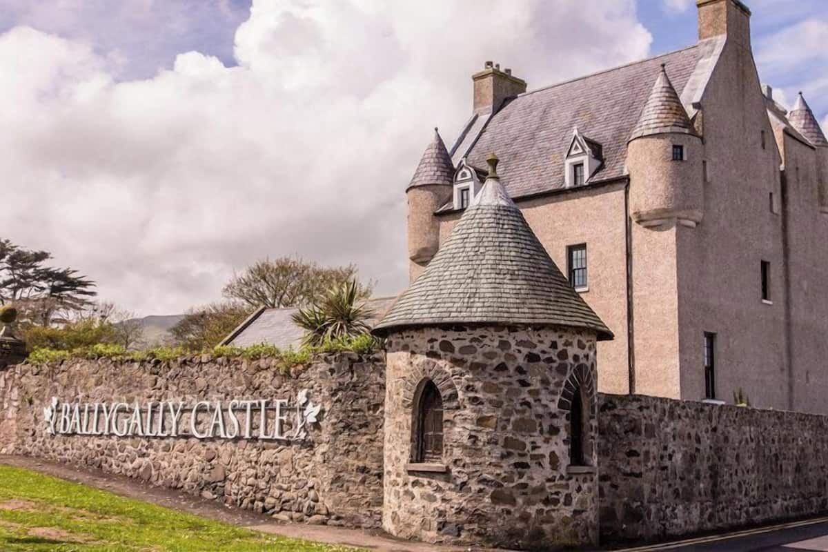 Ballygally Castle with a stone wall and a sign.
