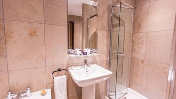 A modern bathroom with a glass-enclosed shower, a pedestal sink, and a mirror above the sink.