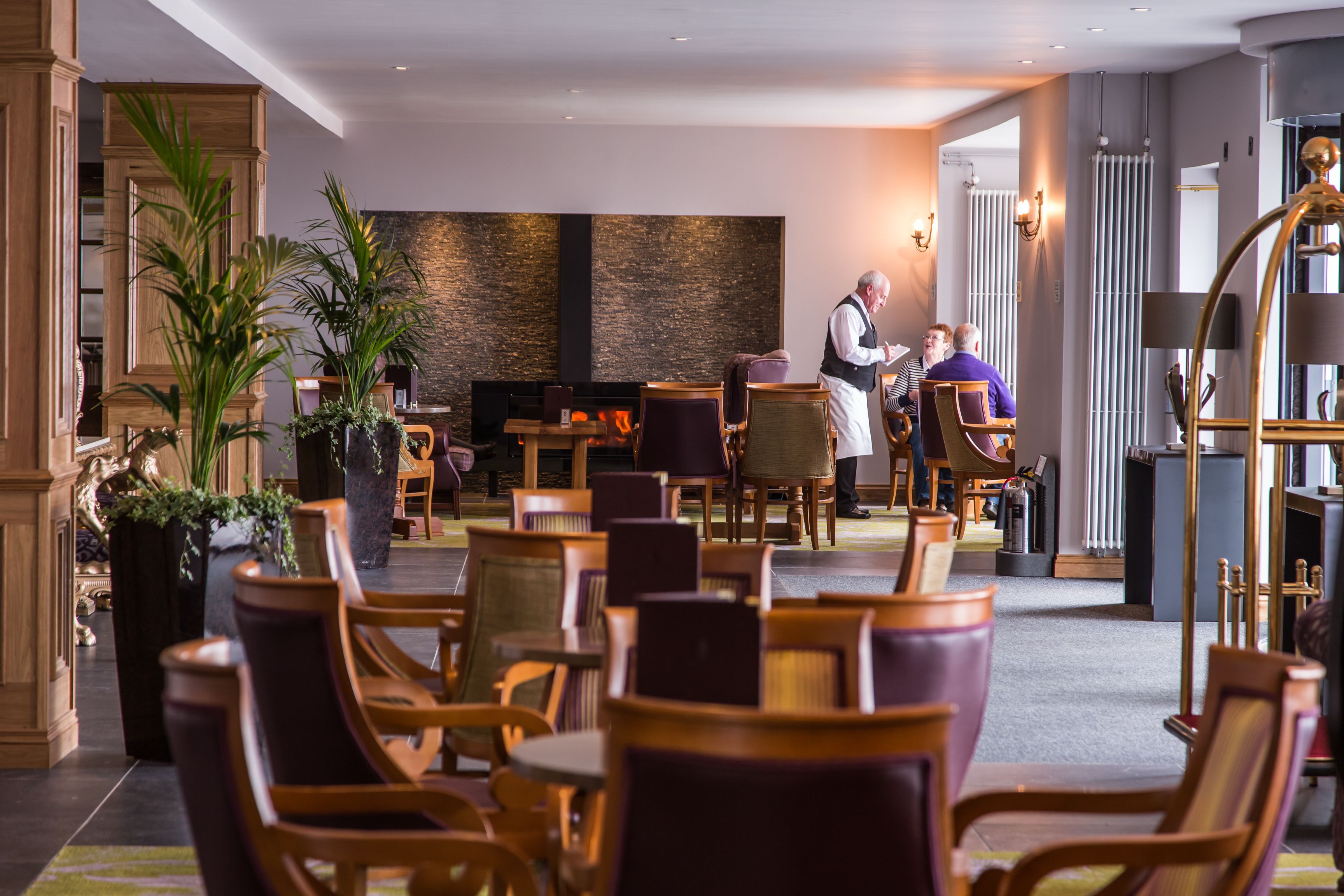 Un vestíbulo de hotel con muebles de madera, una chimenea y una zona de recepción.