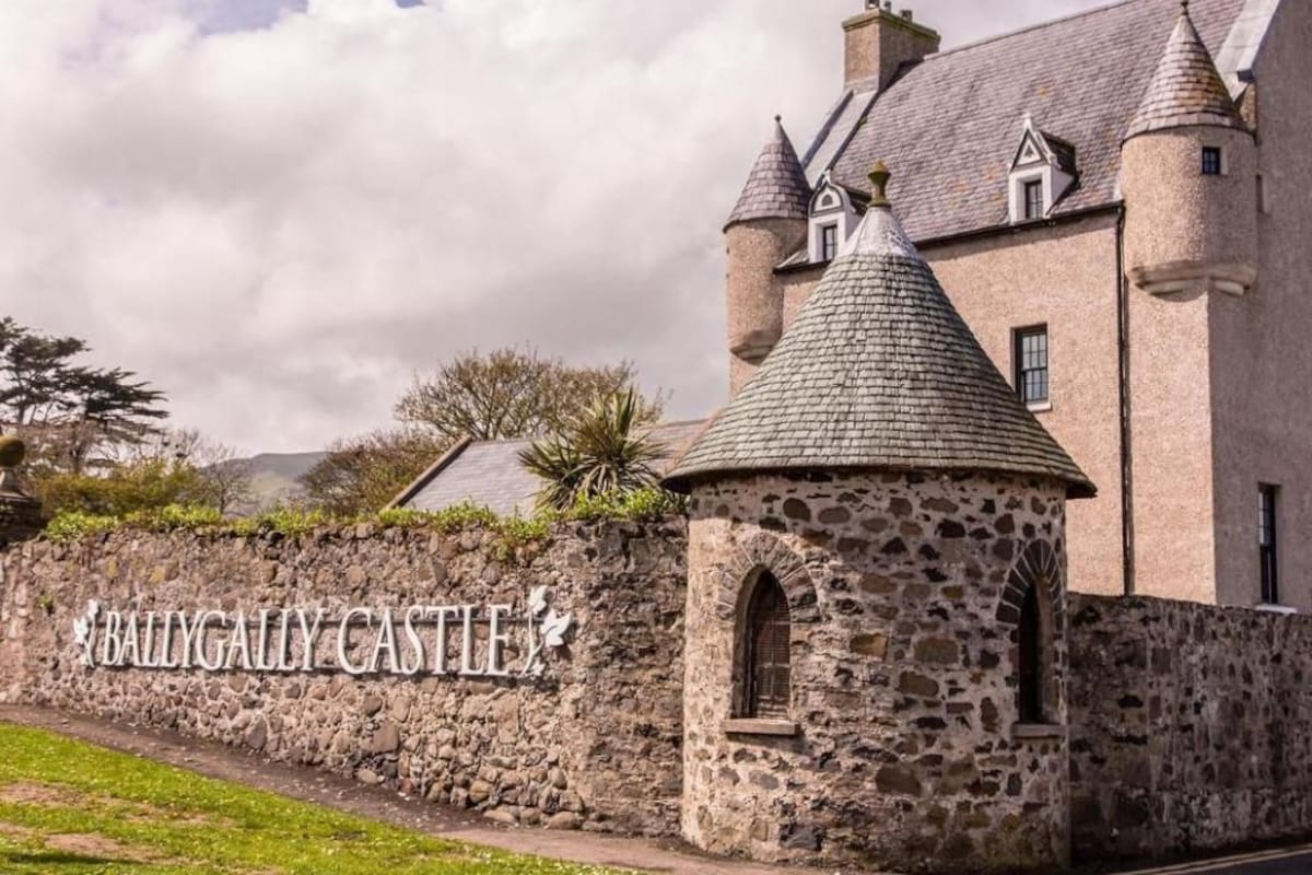 Ballygally Castle mit einer Steinmauer, einem runden Turm und einer traditionellen Burgfassade.