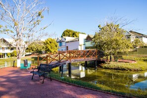 A park with a bridge, a bench, and a pond.