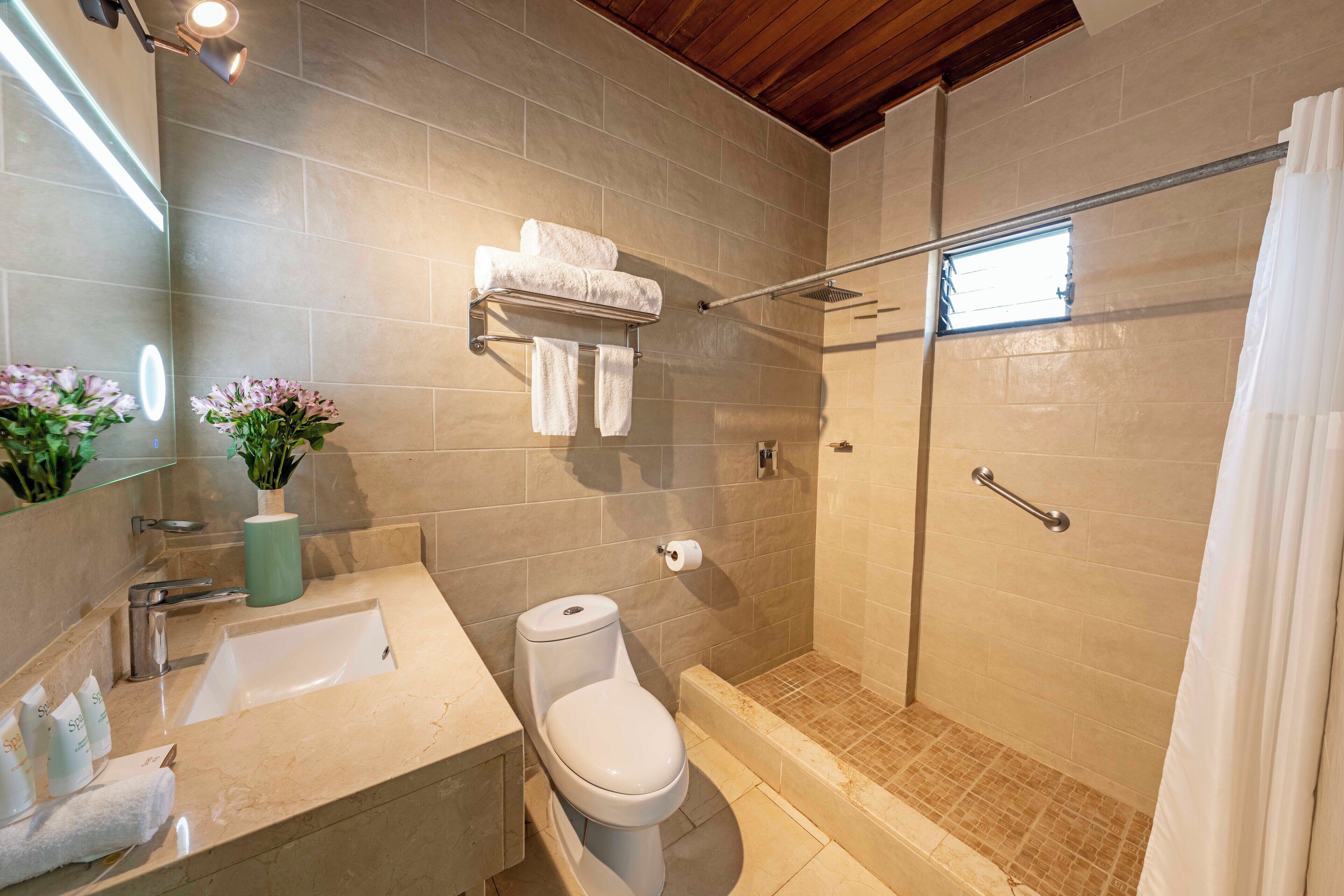 A modern bathroom with a shower, toilet, sink, and a towel rack.
