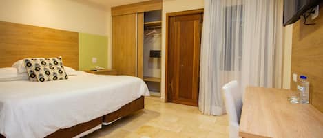 Un dormitorio con cama, mesita de noche, armario de madera y un escritorio con silla.
