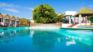 Una piscina al aire libre, sombrillas, sillones reclinables de piscina
