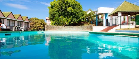 Una piscina al aire libre, sombrillas, sillones reclinables de piscina