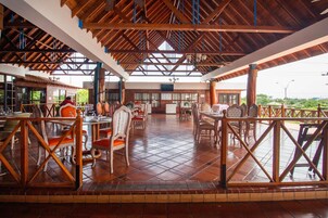 Un comedor interior con mobiliario de madera, piso de baldosas y techo alto con vigas a la vista.
