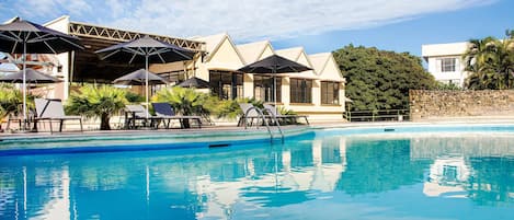 Una piscina al aire libre, sombrillas, sillones reclinables de piscina