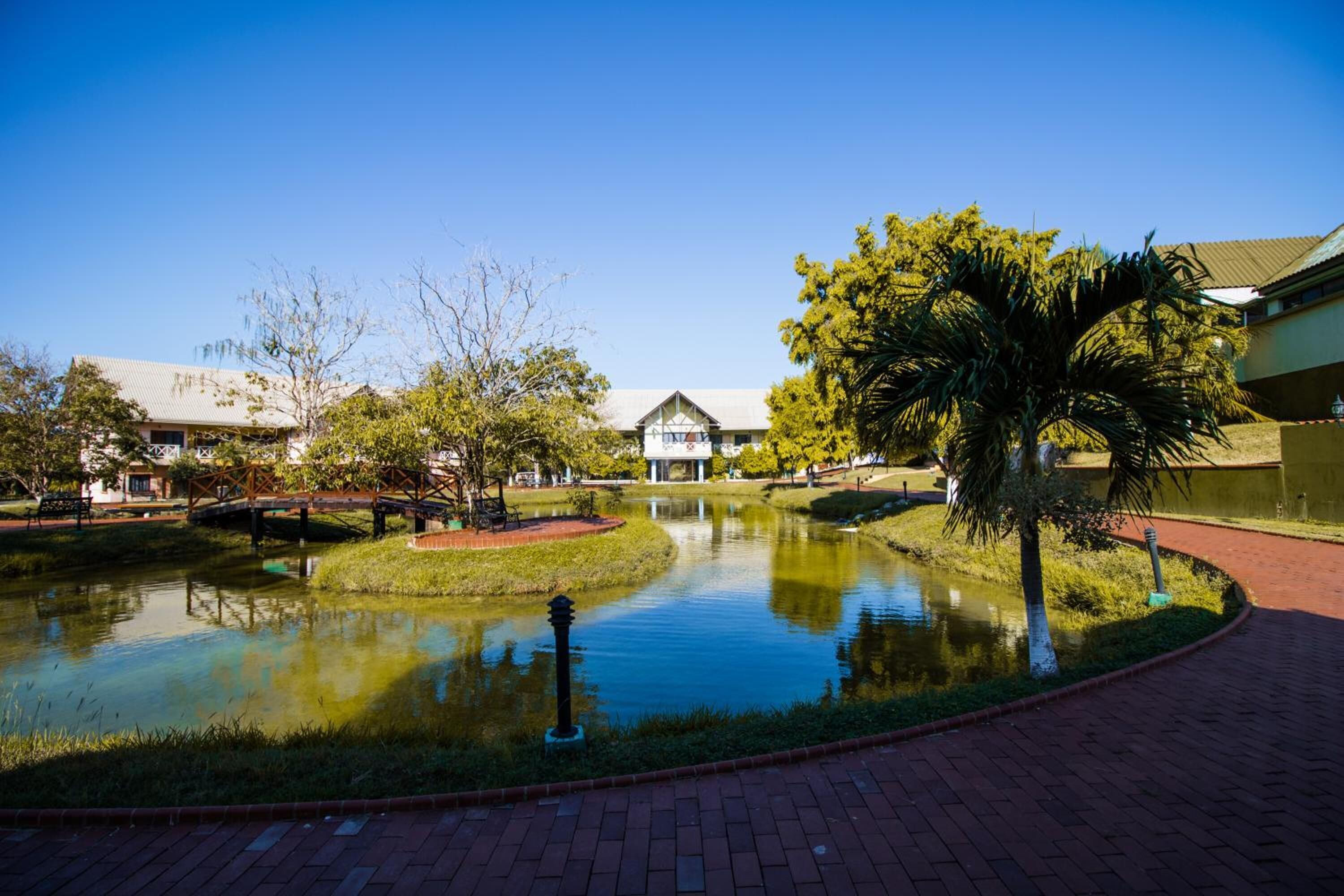 A serene courtyard with a pond, a bridge, and a building in the background.