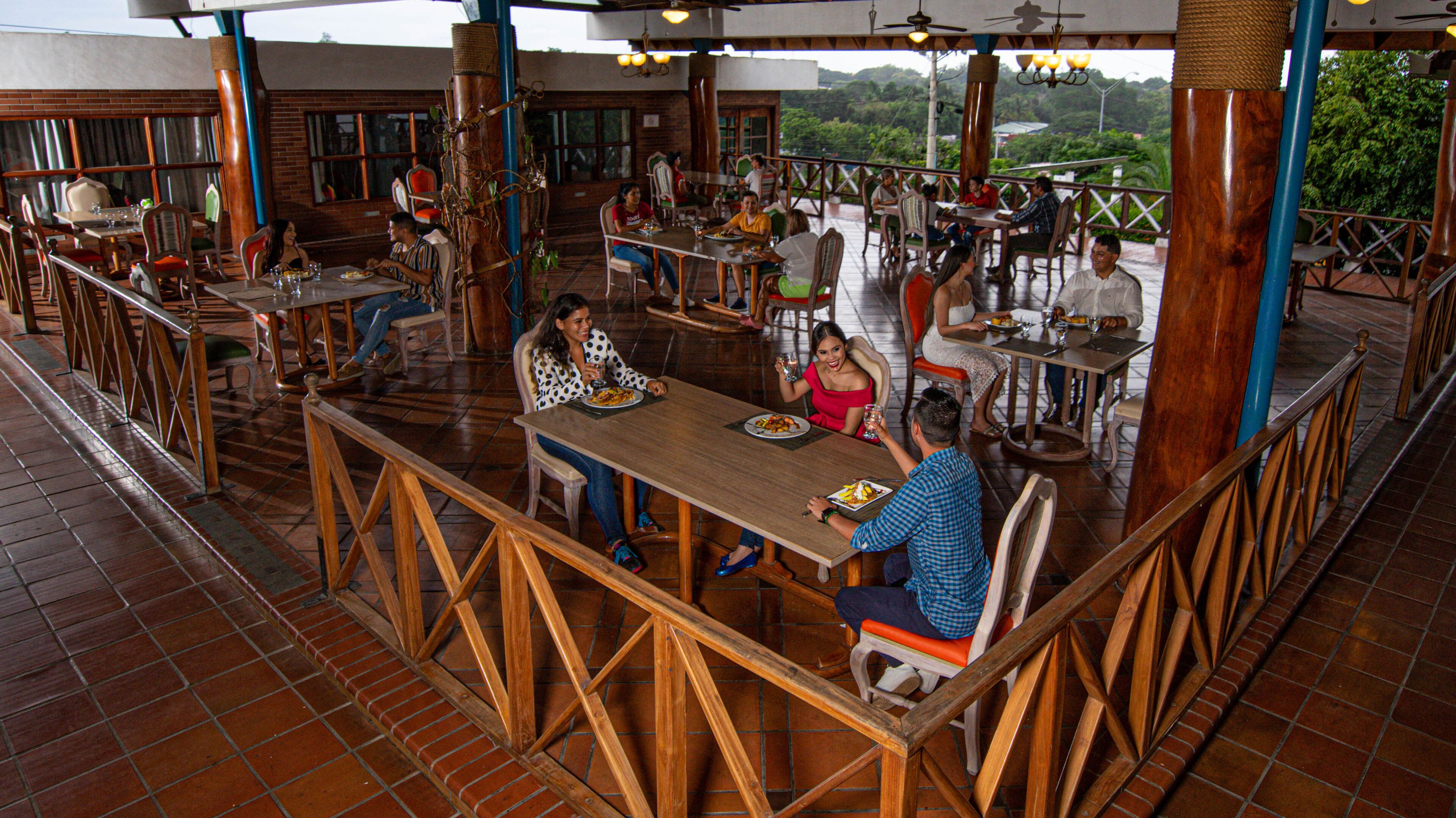 A restaurant with outdoor seating, brick flooring, and a view of the surrounding landscape.