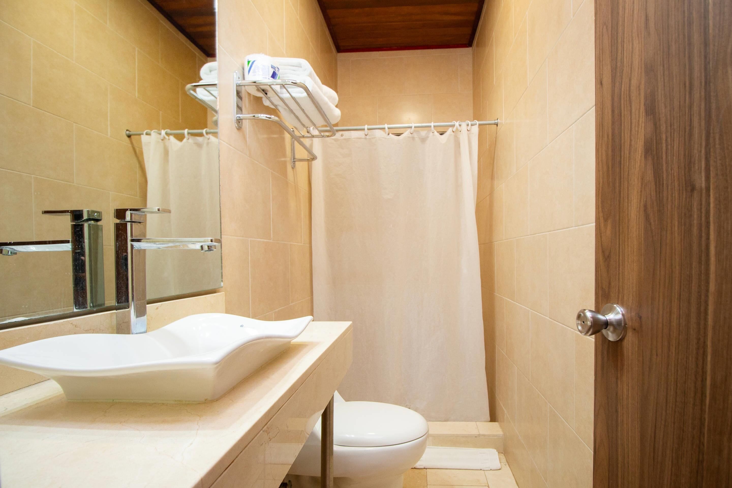 Baño con lavamanos, inodoro, cortina de ducha y un perchero.