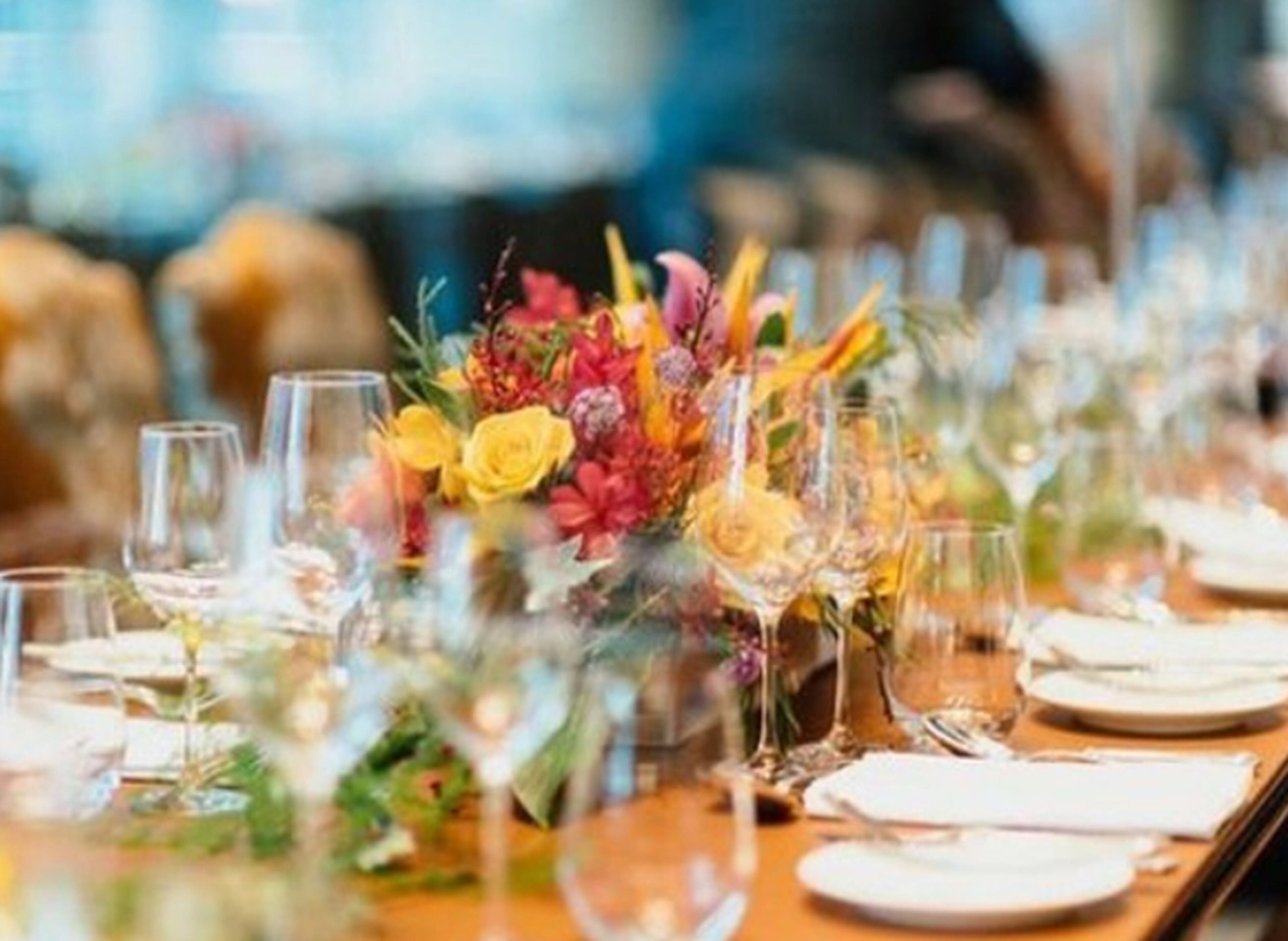 Een eettafel gedekt met verschillende wijnglazen en borden, met een bloemstuk als decoratie.