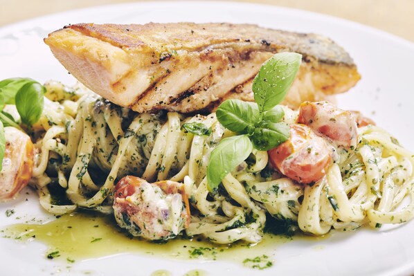 A plate of pasta with chicken, garnished with basil leaves and olive oil.