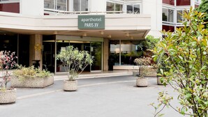 Un hotel-apartamento con fachada moderna, grandes ventanales y un cartel que indica que se encuentra en París.