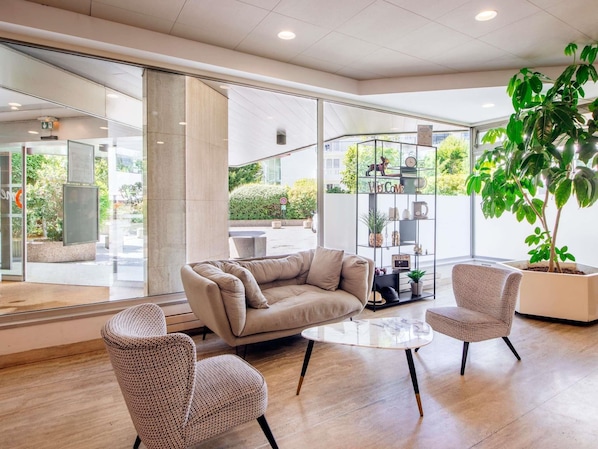 Un intérieur moderne avec un canapé, deux fauteuils, une table basse et une grande plante en pot.